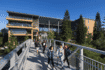 View of UC Irvine building with Solar Canopy covering courtyard with walking bridge in foreground and people walking across.