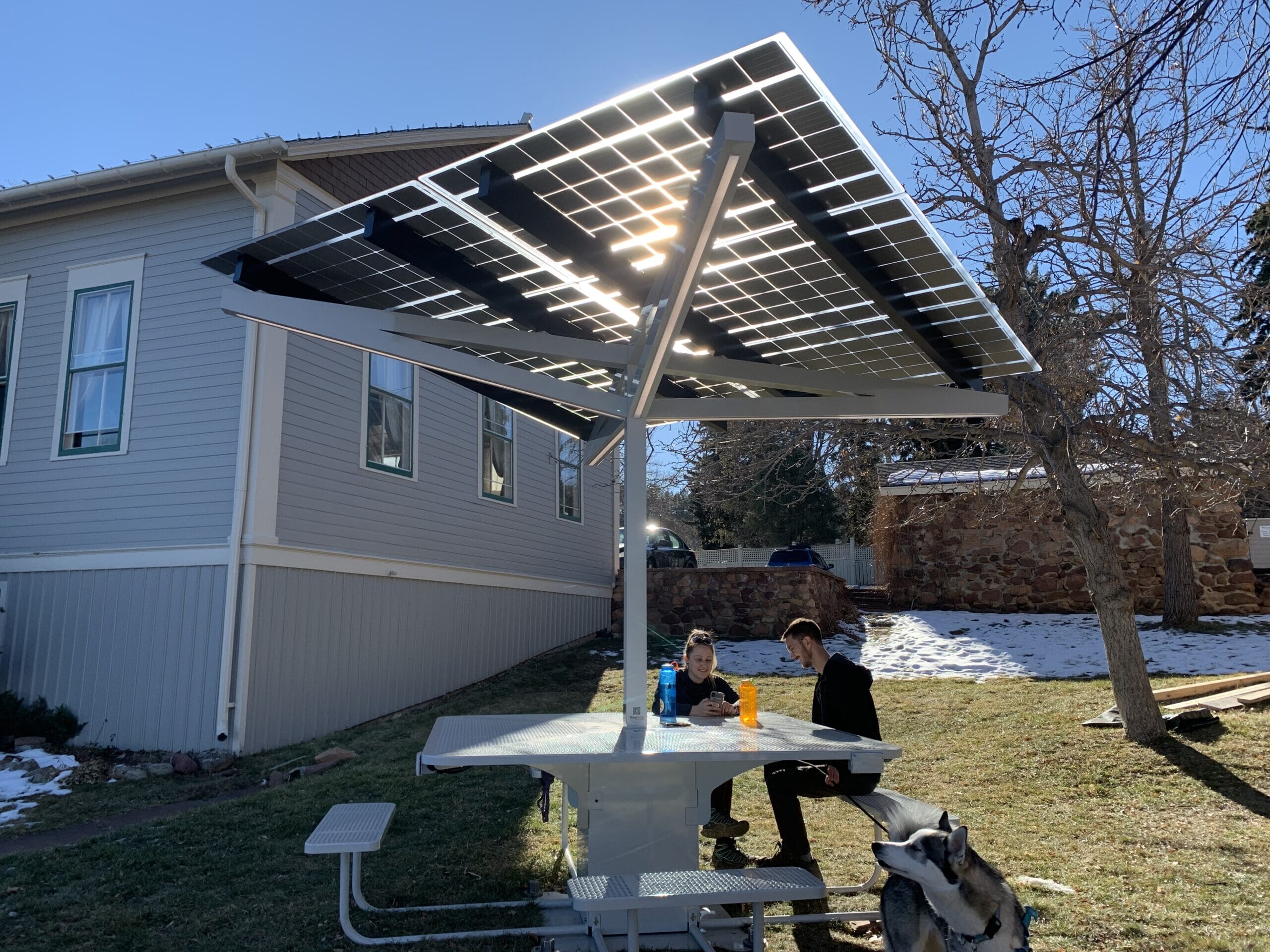 Solar Charging Table on lawn in Chautauqua Park, Boulder Colorado with people sitting and using cell phones.