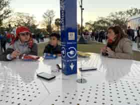 SolarZone Solar Charging Table with three people sitting at benches and mobile phones wirelessly charging