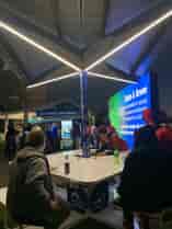 Solarzone Recharge Station with people sitting on benches under solar shade with LED Lighting at night time.