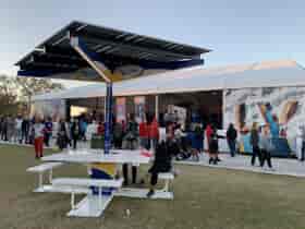 Solar Recharge Station on lawn in front of Super Bowl LV Experience with people sitting and walking by.