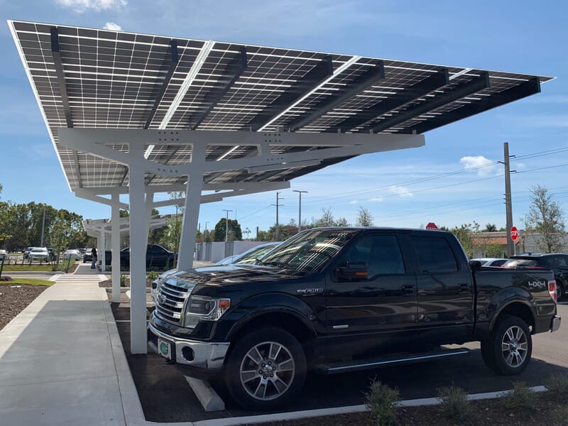 SolarScape Solar Carport covering parking spaces with cars parked in front with blue sky in background