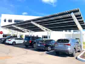 SolarScape Solar Carport with front view of Solar Panels, covering parking spaces with cars parked in front of white office building