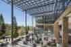 Solar Panel Awning over outdoor student area with large structural beams and tables with students sitting, studying walking around with trees in the background