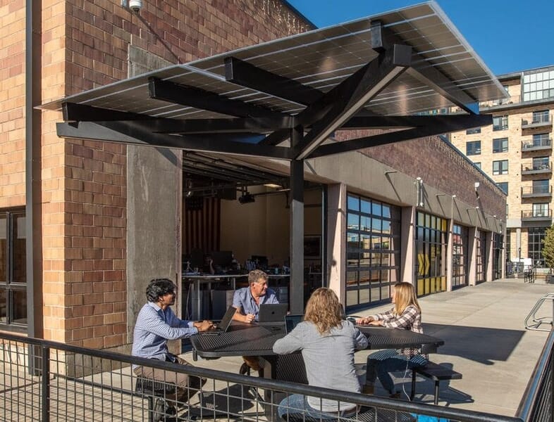 SolarZone charging workstation outside of office building with people working and charging mobile devices in downtown Denver, CO