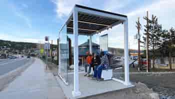 Solar powered bus stop shelter provides protection, shade, wireless charging, wifi and lighting for people waiting at the bus stop.